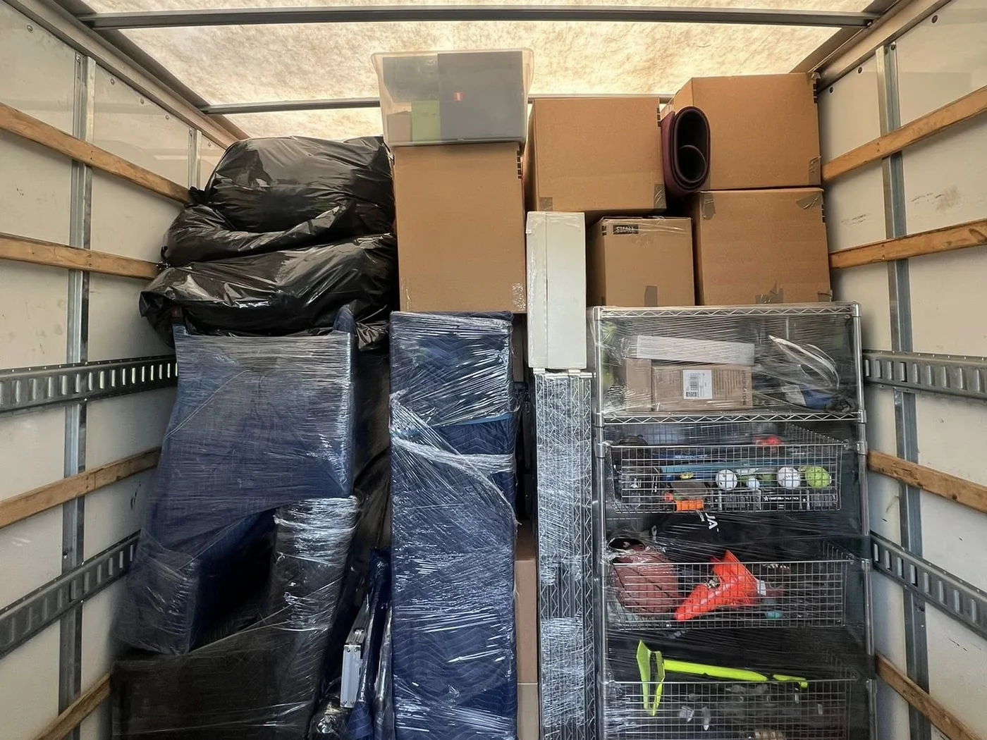 Organized moving truck with protected furniture, boxes, and shelving