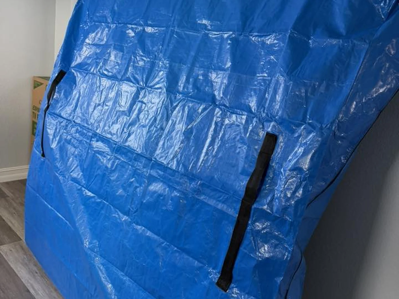 Large household item secured inside a blue moving cover
