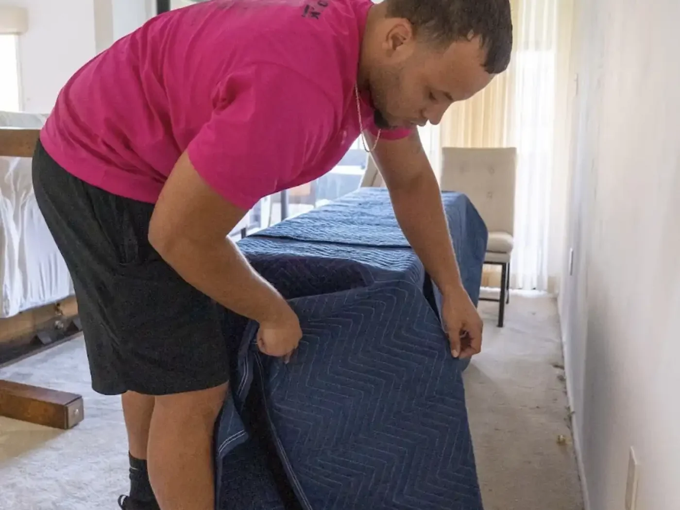 Mover placing a protective moving blanket around furniture