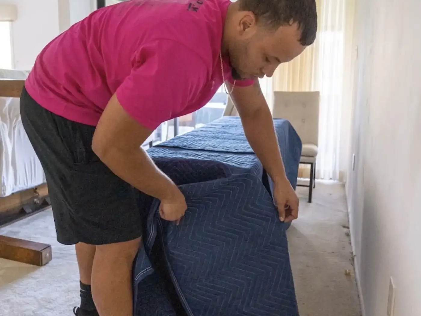 Mover wrapping household furniture with a moving blanket