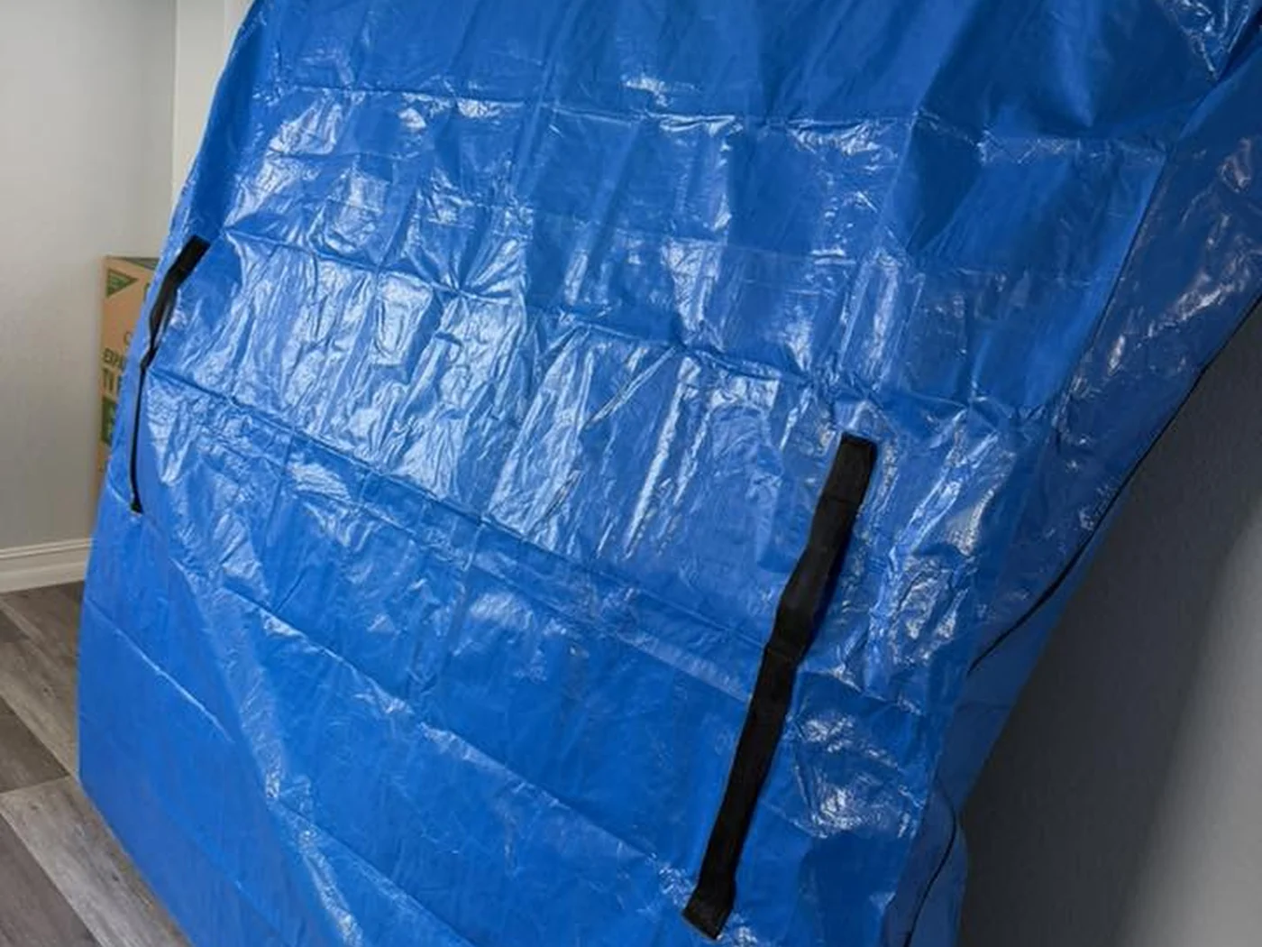 Large household item protected in a blue moving cover